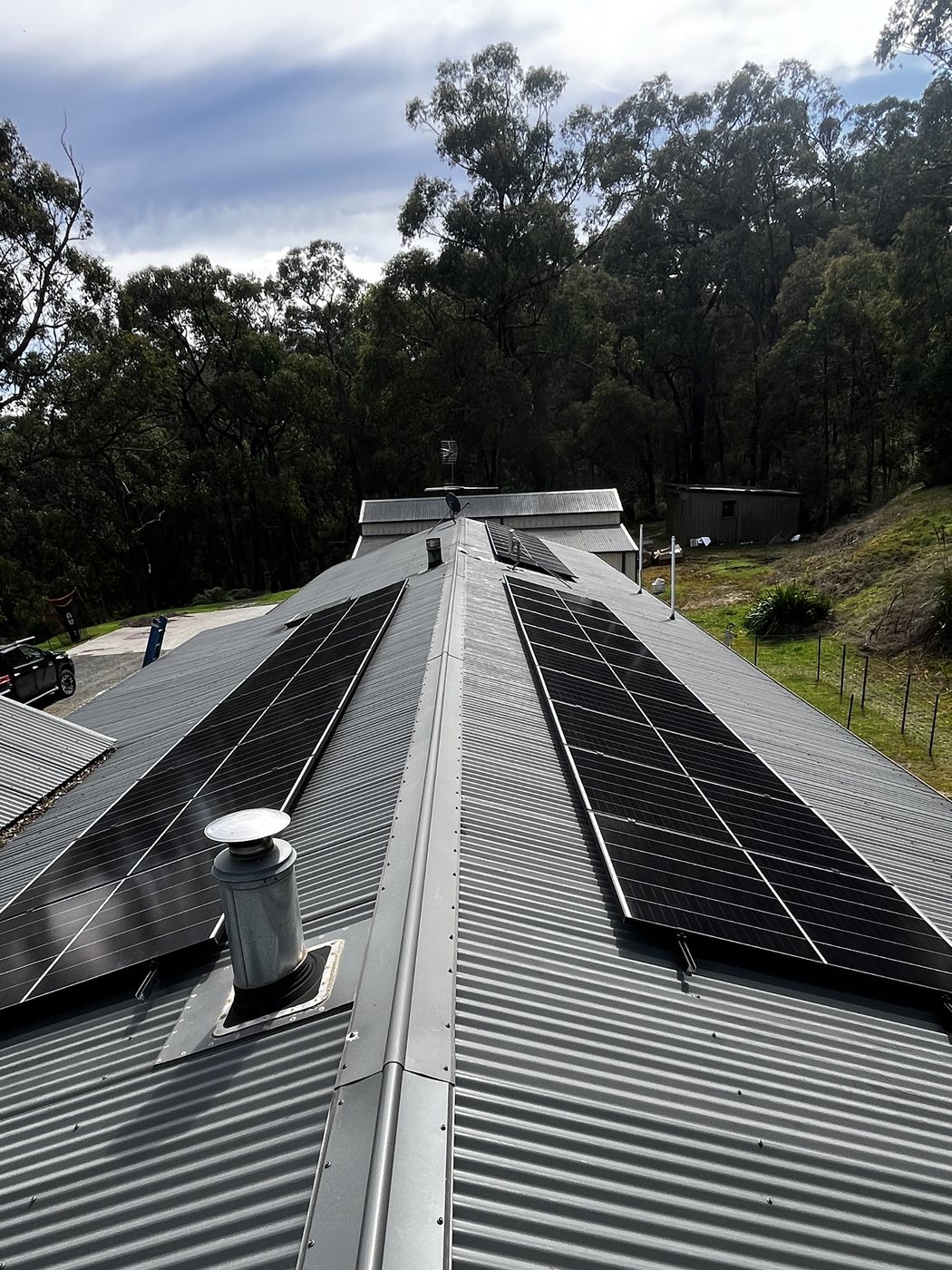 Two solar arrays installed either side of a corrugated steel roof ridge on a bush property, installed by SALTD Electrical